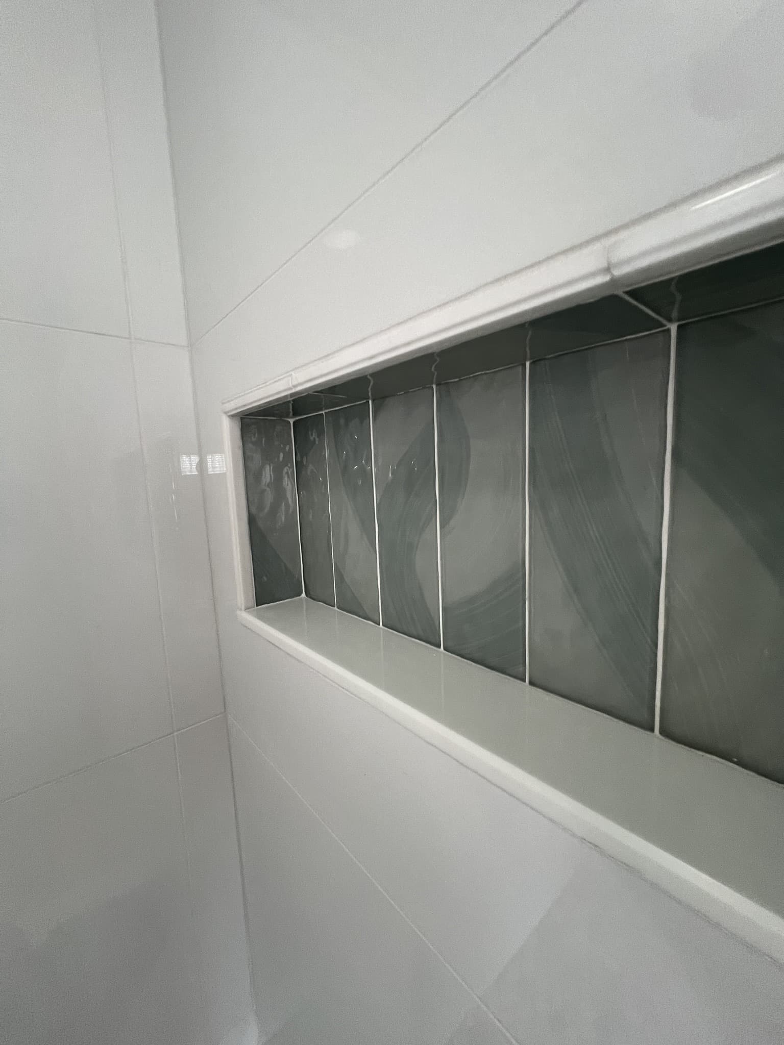 Tiled shower niche lined with glossy dark green tile set into white large-format walls — Karhan Construction, Orlando