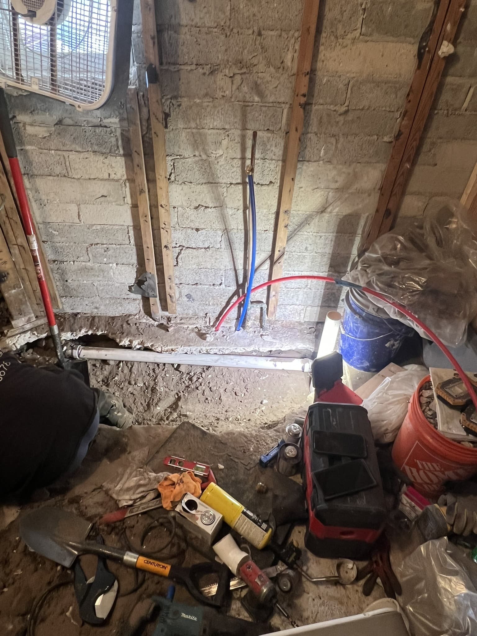 Bathroom demolished to concrete block wall with red and blue PEX lines and tools scattered on the subfloor — Karhan Construction, Orlando
