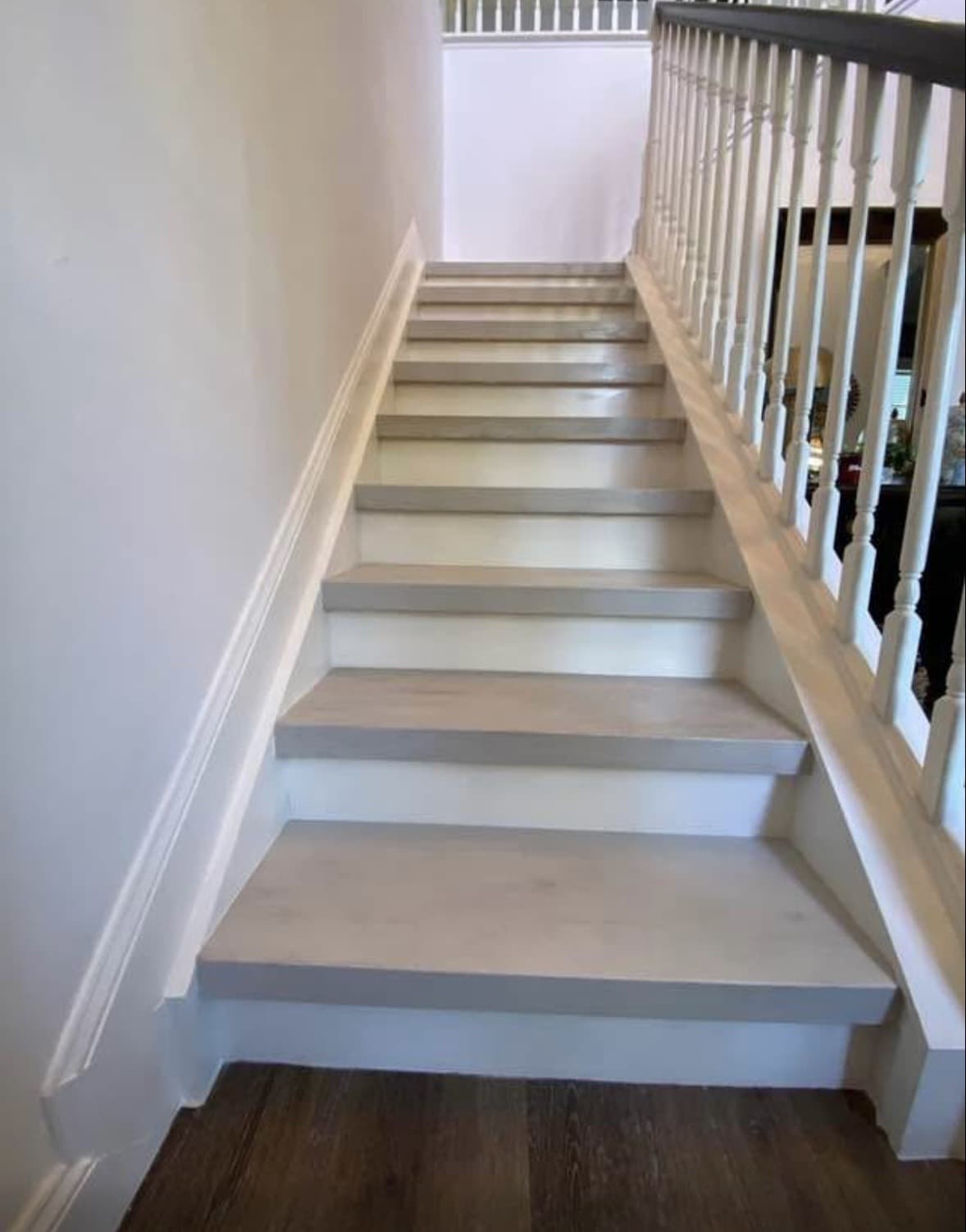 Staircase with whitewashed light-gray wood treads and white risers beside white turned-spindle balusters — Karhan Construction, Orlando