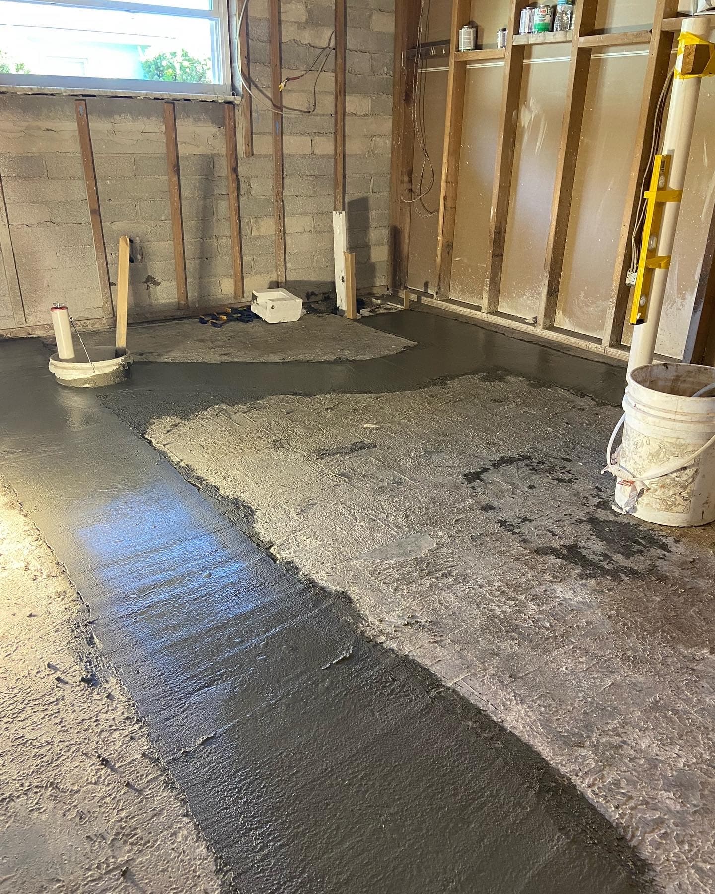 Wood-framed interior room with a fresh wet concrete floor patch poured around a pipe cutout over the old slab — Karhan Construction, Orlando