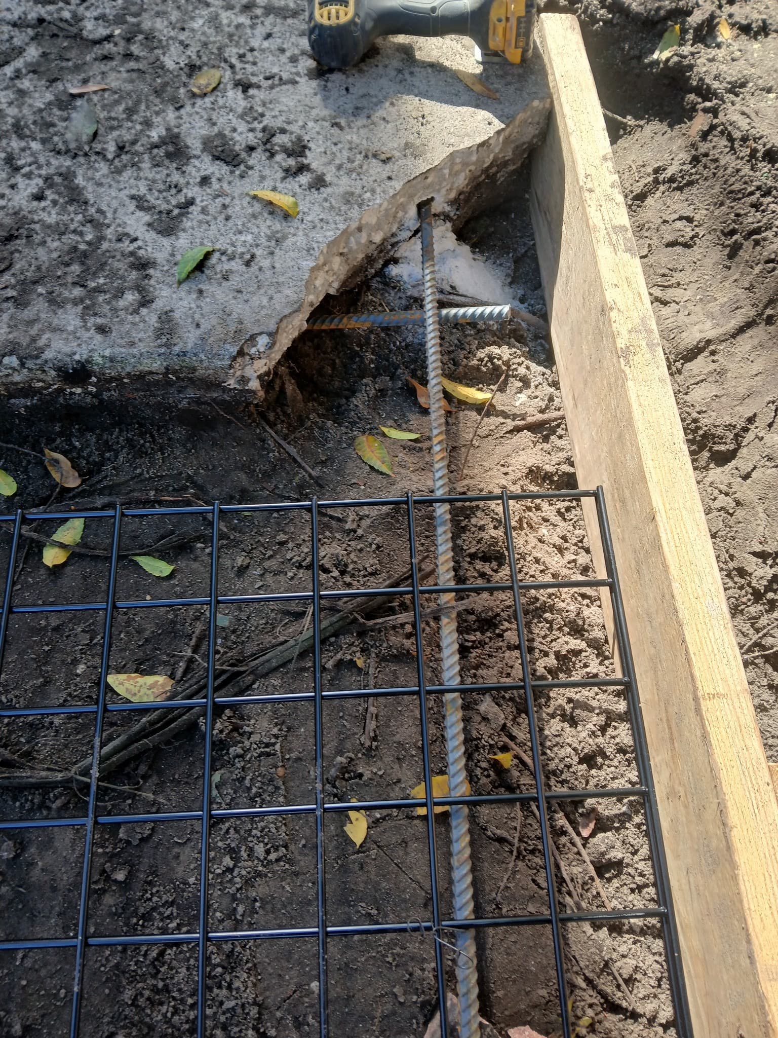 Rebar dowel and wire mesh reinforcement laid over soil beside a broken slab edge before a concrete pour — Karhan Construction, Orlando