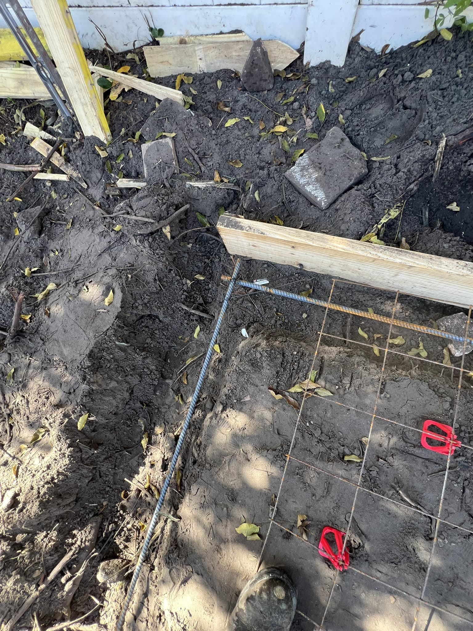Footing trench with wire mesh and rebar reinforcement on soil held by red rebar chairs before the pour — Karhan Construction, Orlando