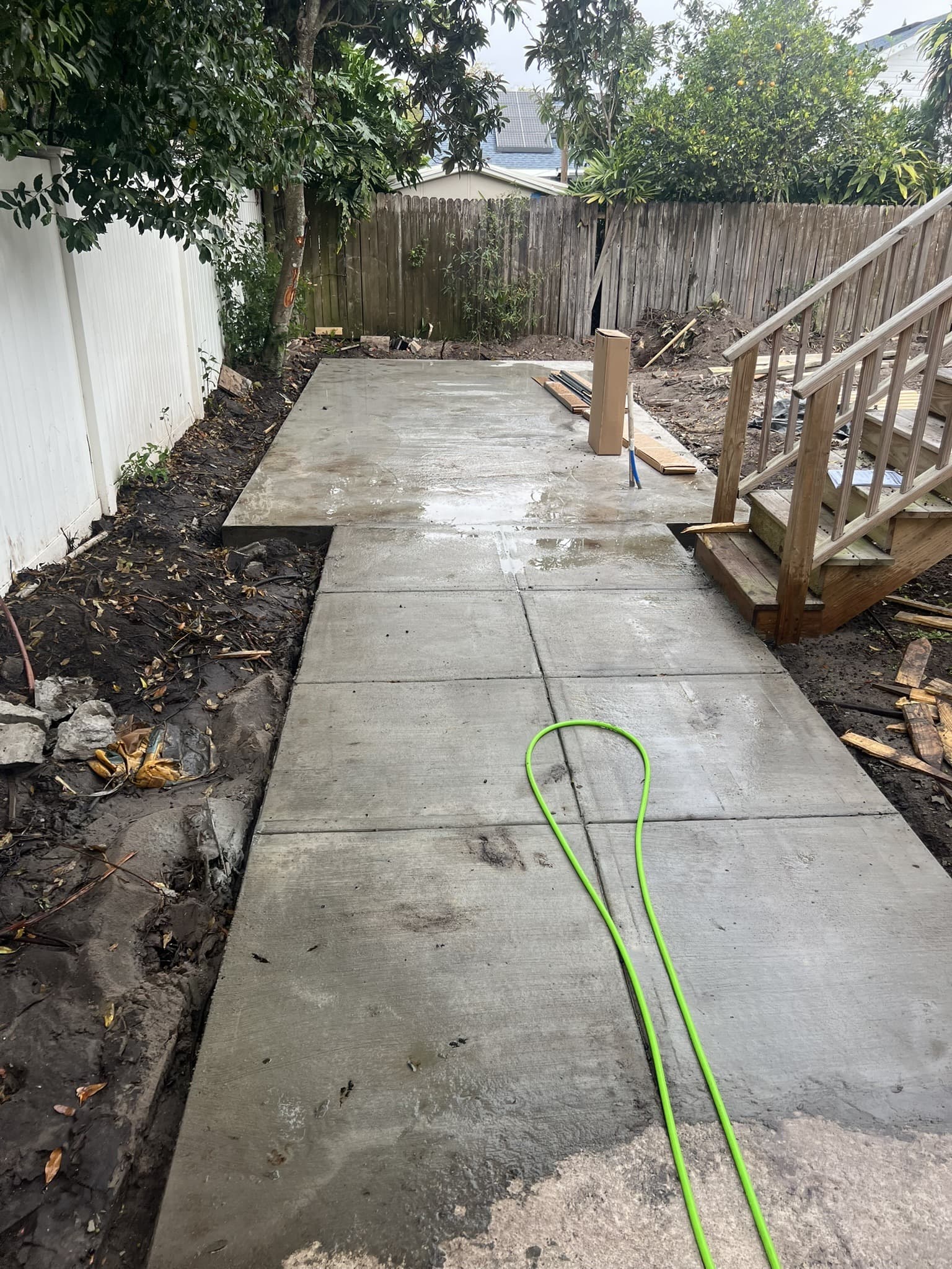 Finished poured-concrete walkway running between a white vinyl fence and wood fence to backyard deck steps — Karhan Construction, Orlando
