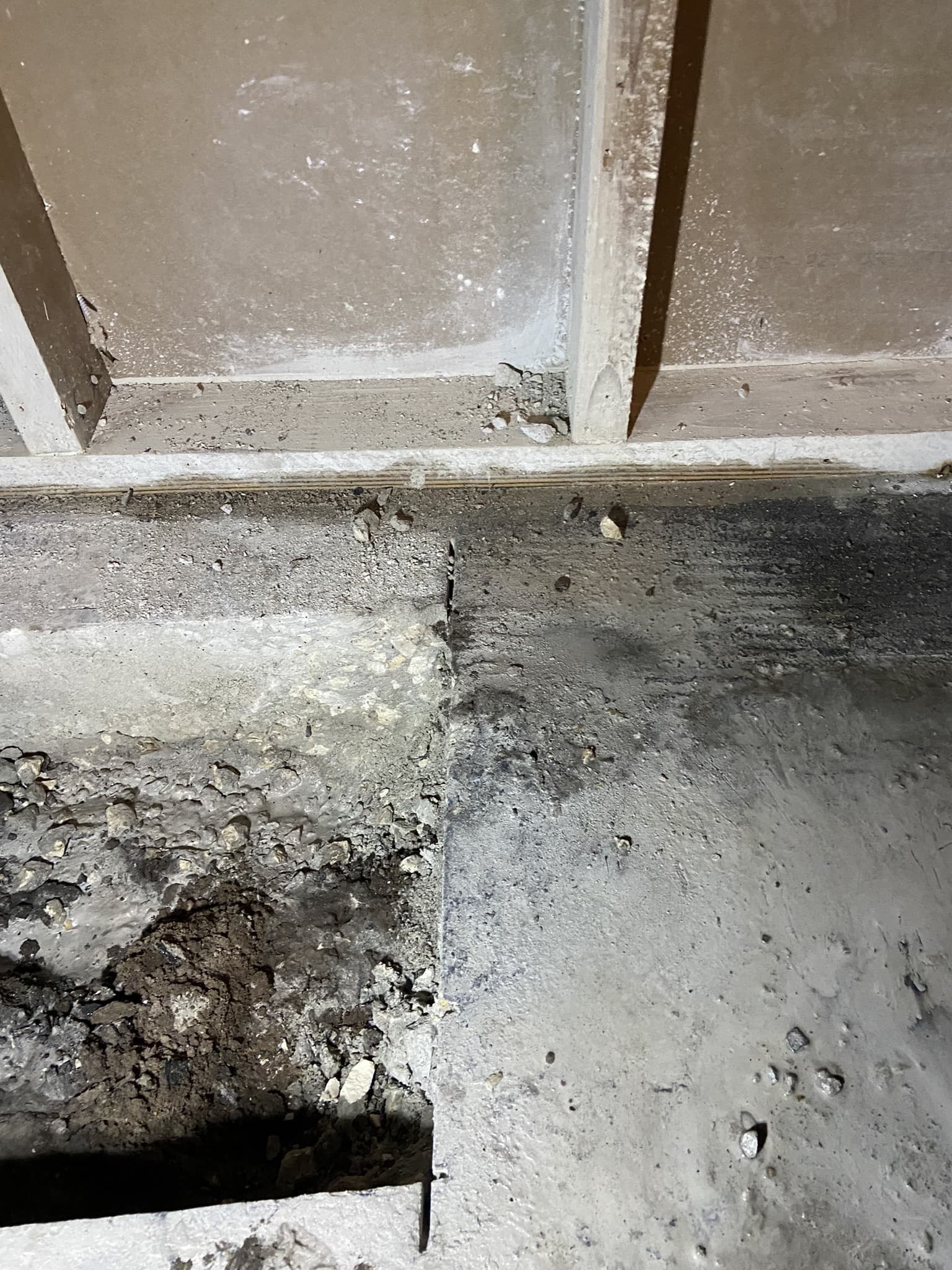 Close-up of a cut slab edge along a stud wall exposing the gravel aggregate base during interior demo — Karhan Construction, Orlando