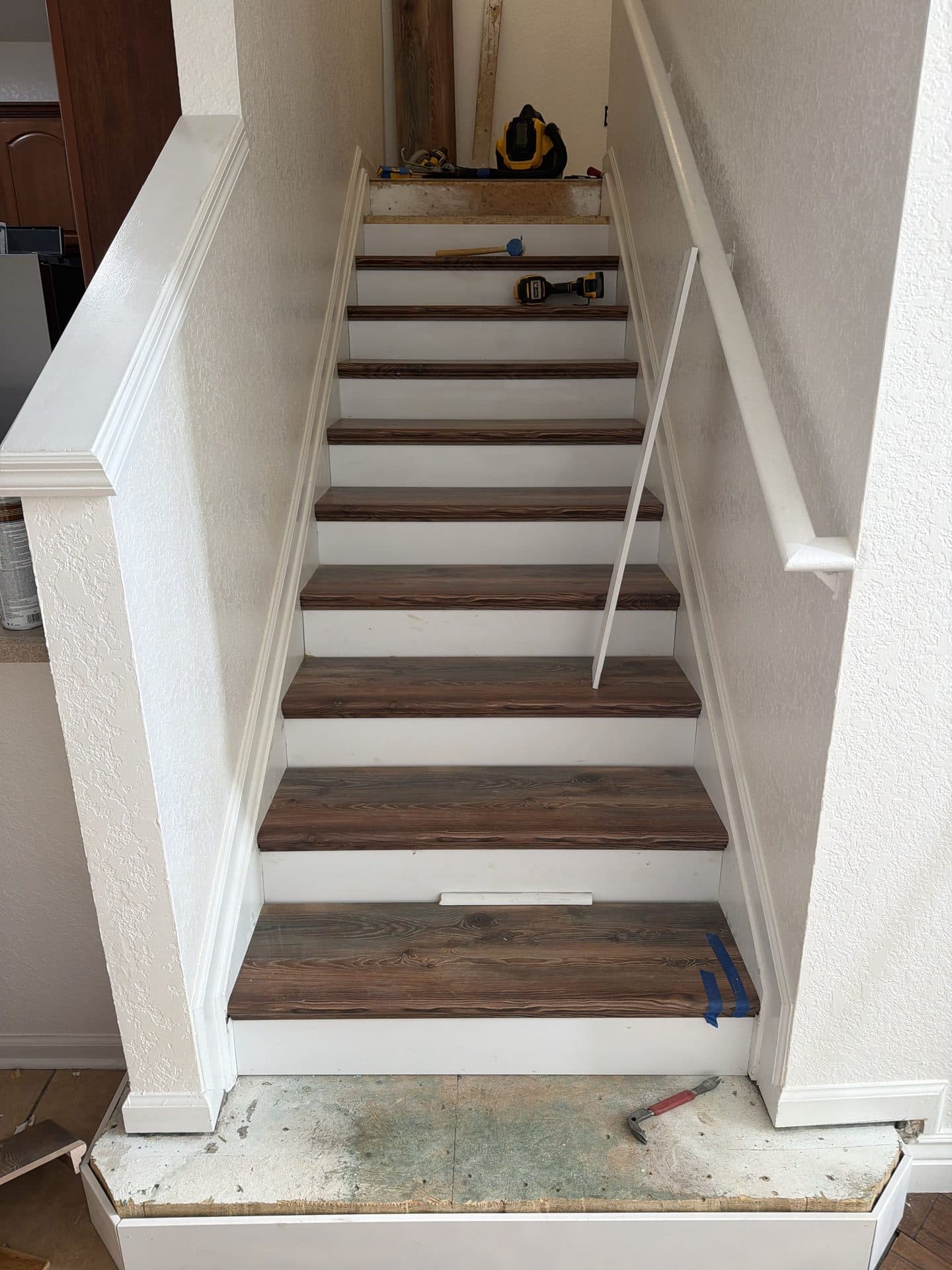 Staircase remodel in progress with new dark wood treads, white risers, and tools resting on the upper steps — Karhan Construction, Orlando