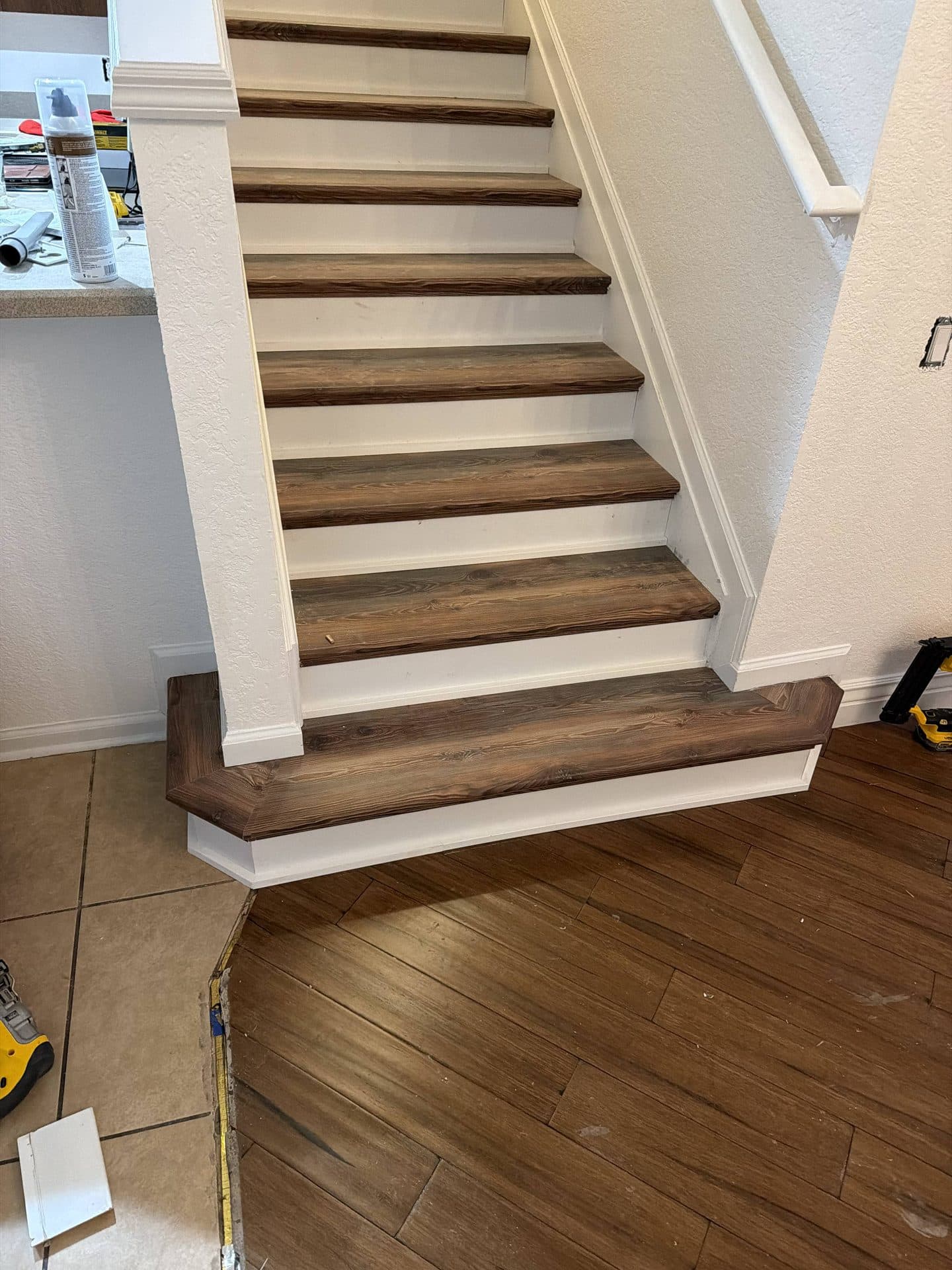Freshly installed dark wood staircase with white risers and a mitered bullnose bottom step meeting plank flooring — Karhan Construction, Orlando
