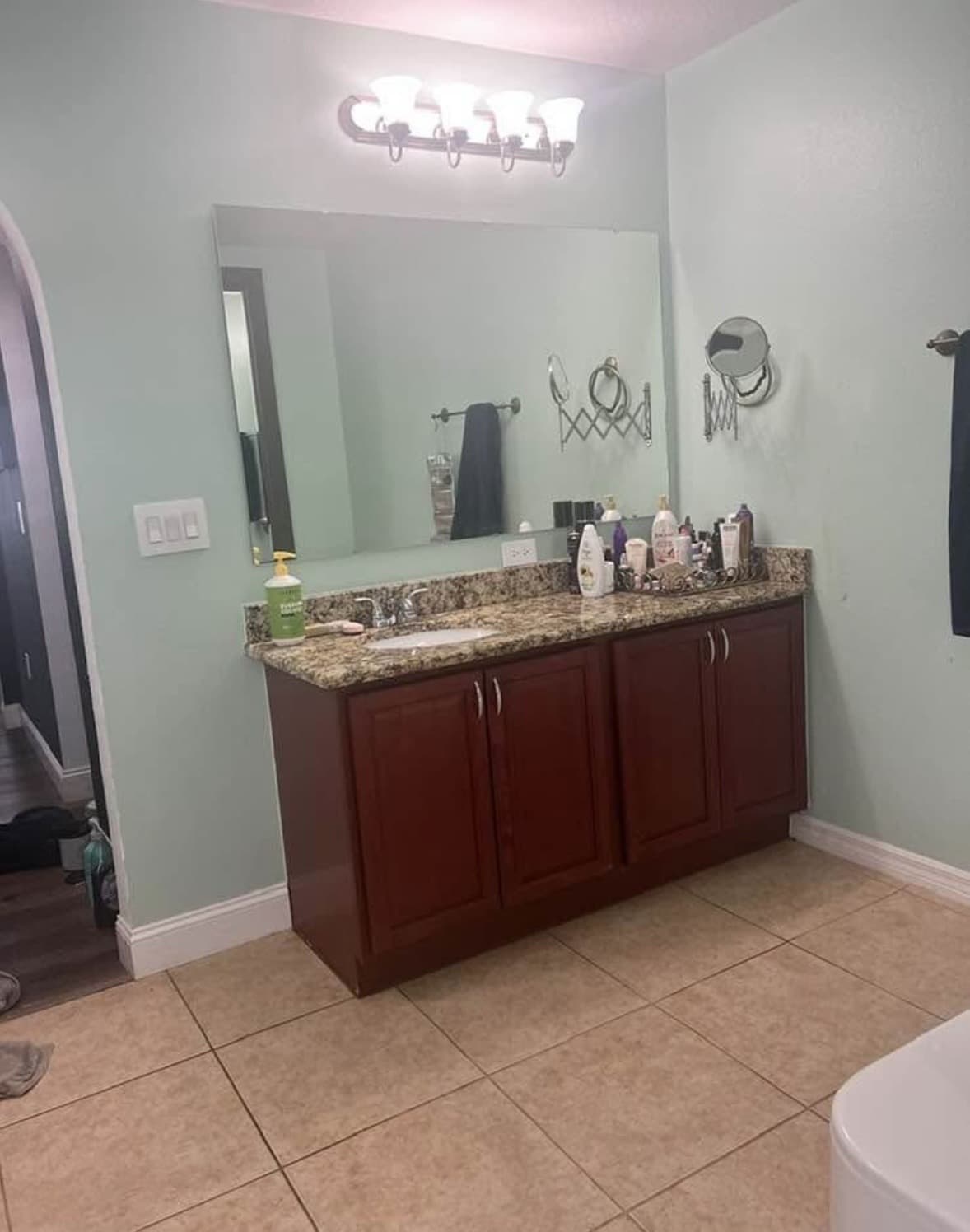 Bathroom vanity with cherry-wood cabinets, granite top, large mirror and a four-light fixture on sage walls — Karhan Construction, Orlando