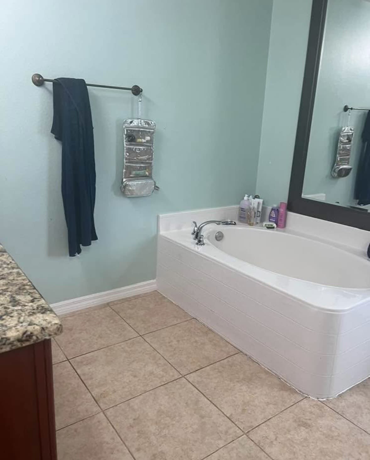 Corner garden tub in a white surround with sage green walls, bronze towel bar and beige tile floor — Karhan Construction, Orlando