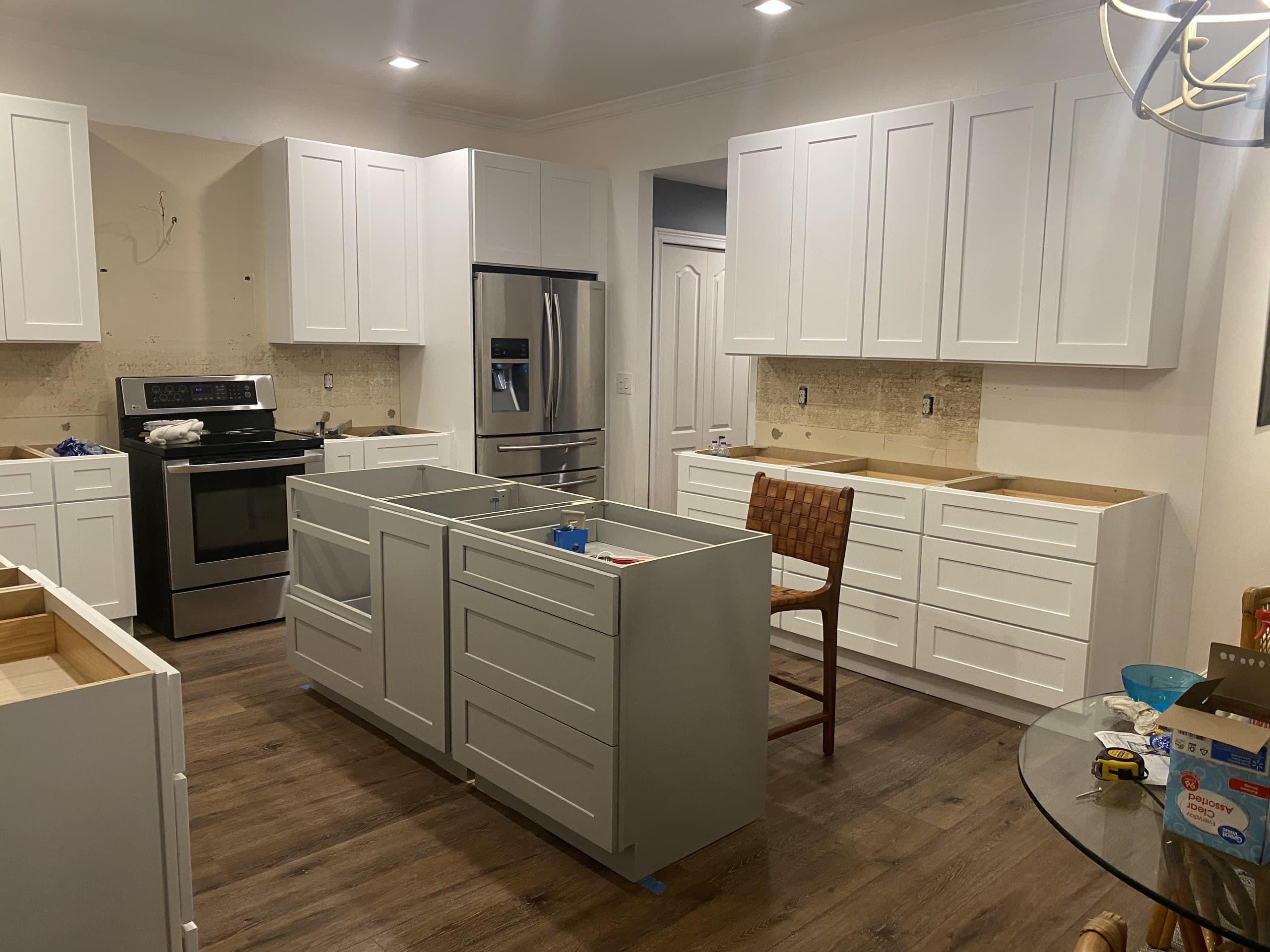 Kitchen cabinets being assembled, gray island base and white wall cabinets with stainless appliances — Karhan Construction, Orlando