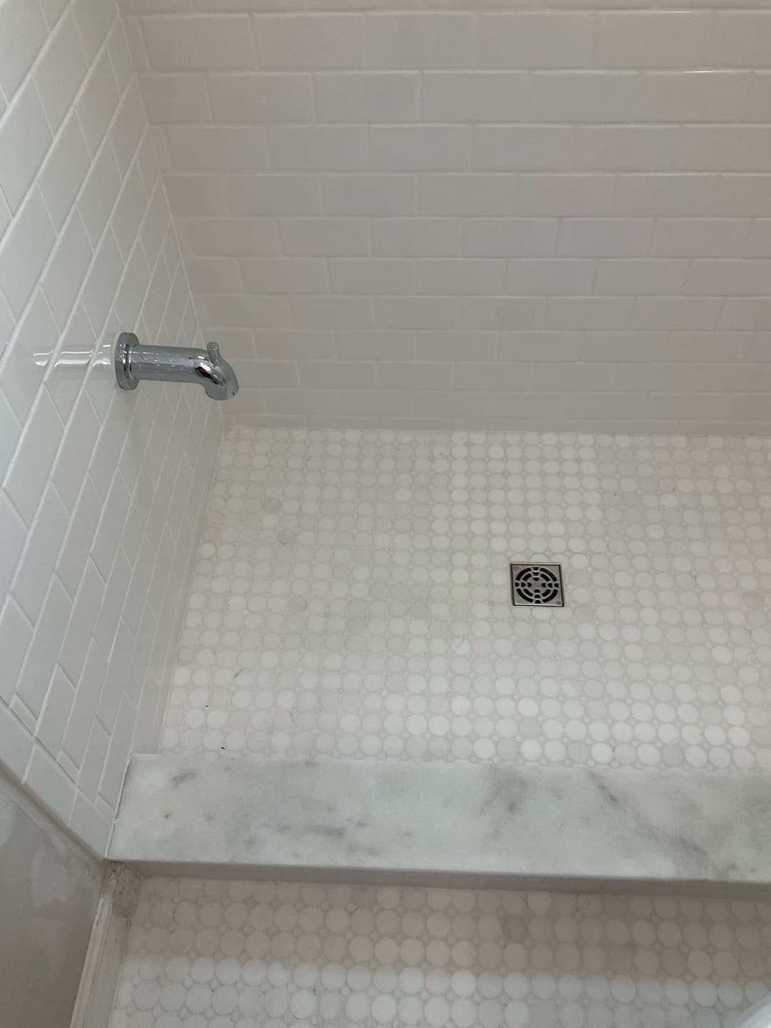 AFTER — finished shower floor with marble penny-round mosaic and marble threshold (real Karhan project)