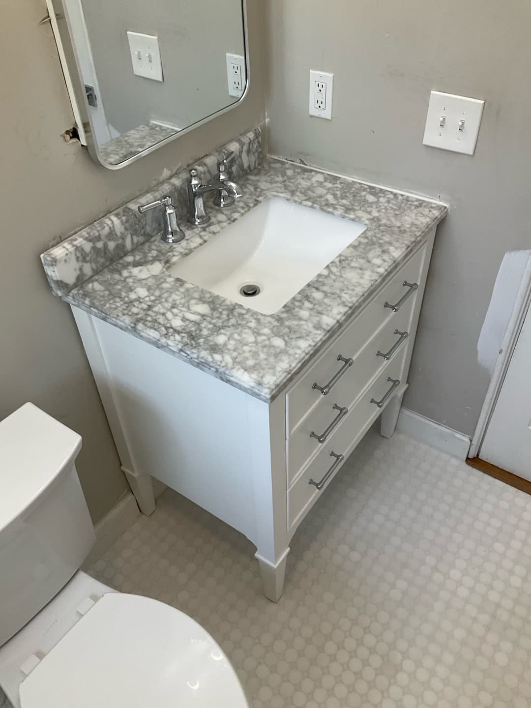 AFTER — new vanity with a marble-look top and polished nickel bridge faucet (real Karhan project)