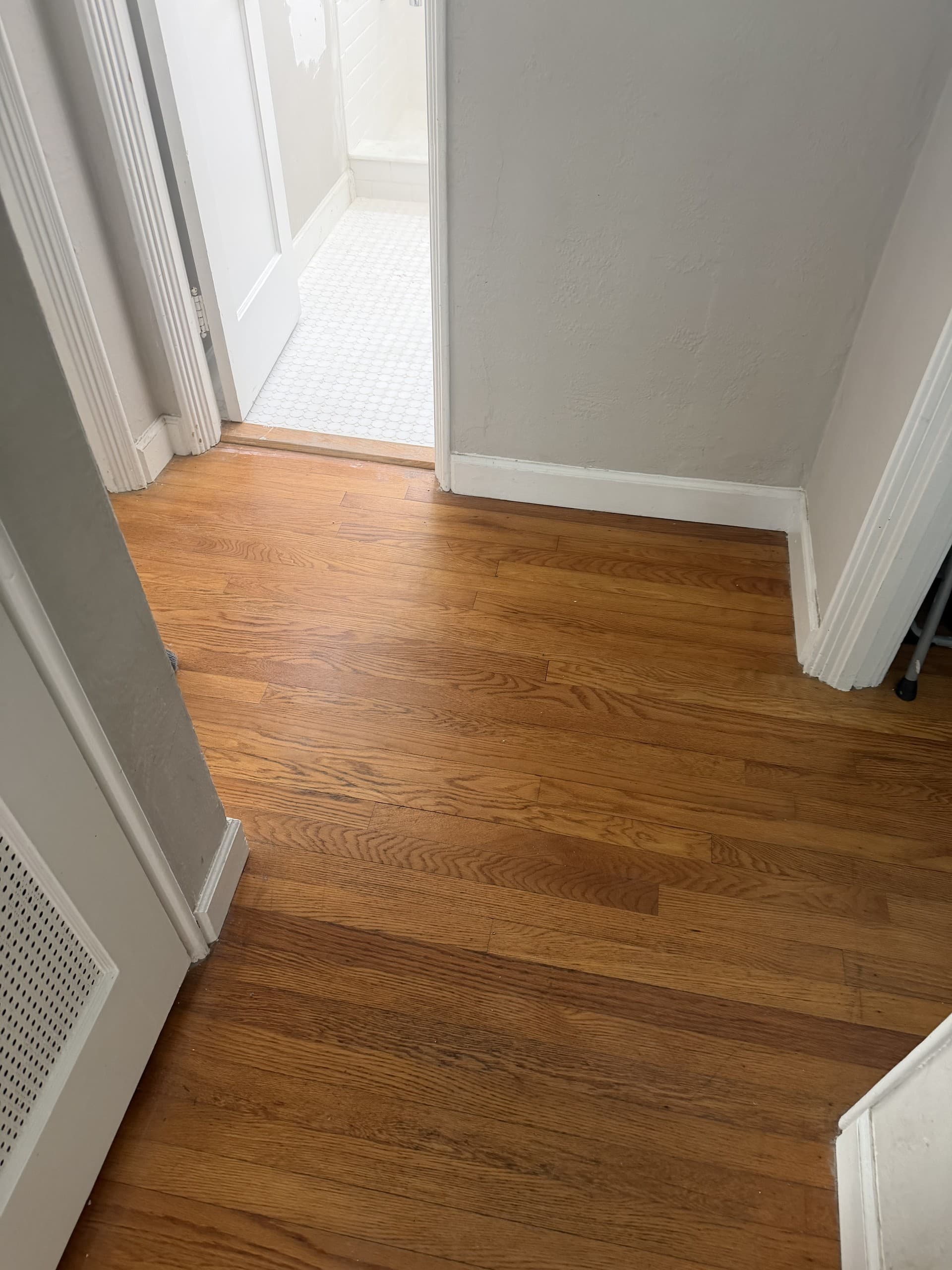 AFTER — refinished hardwood hallway leading into the finished bathroom (real Karhan project)