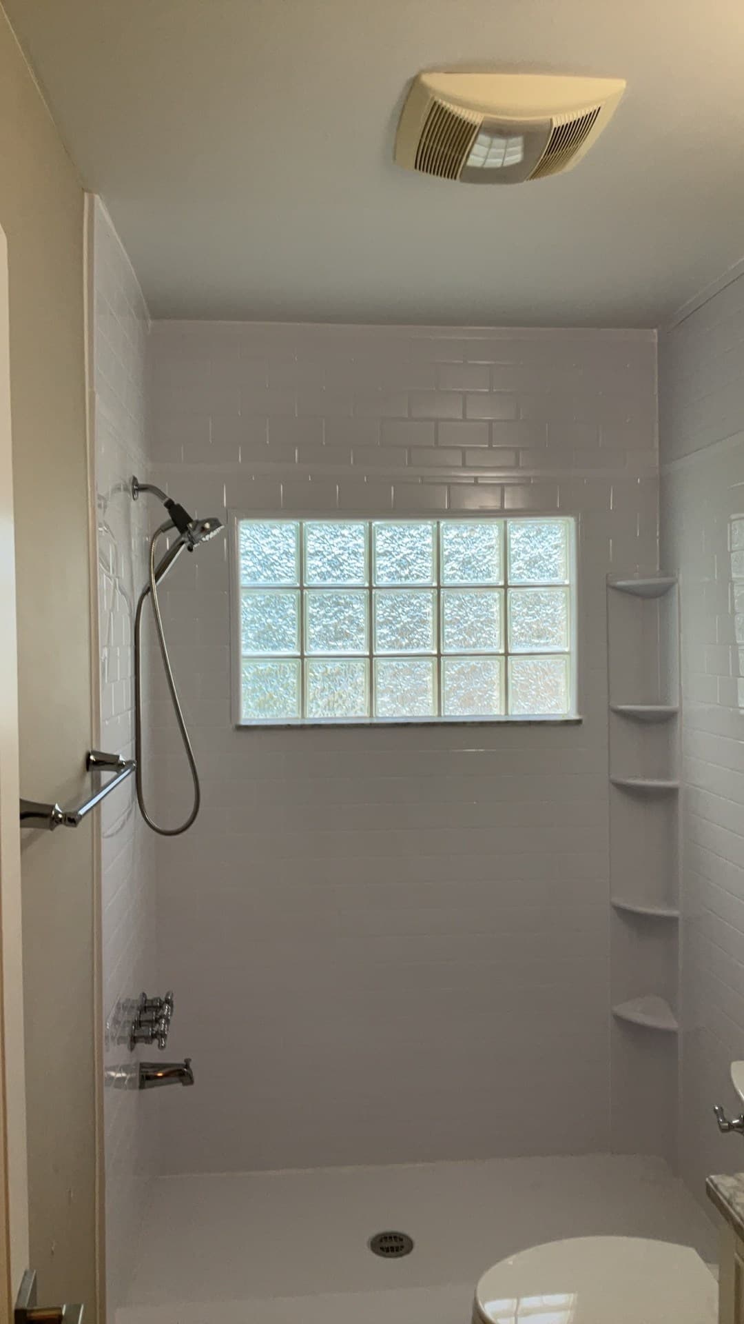 AFTER — wide view of the finished shower with white subway tile, the kept glass-block window, and a new molded corner shelf (real Karhan project, College Park)