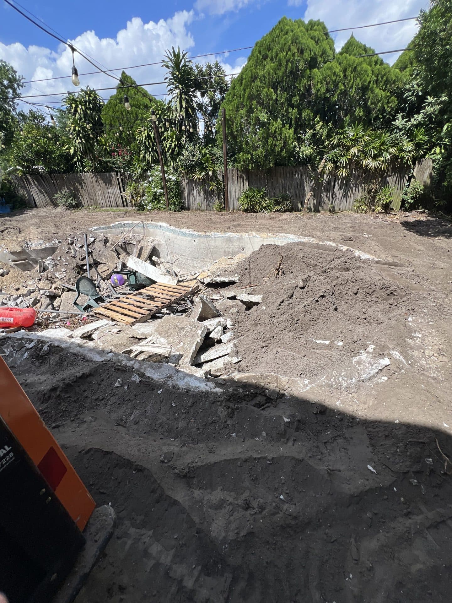 DURING — pool being backfilled, one end piled with dirt and the shell still holding broken concrete (real Karhan project)