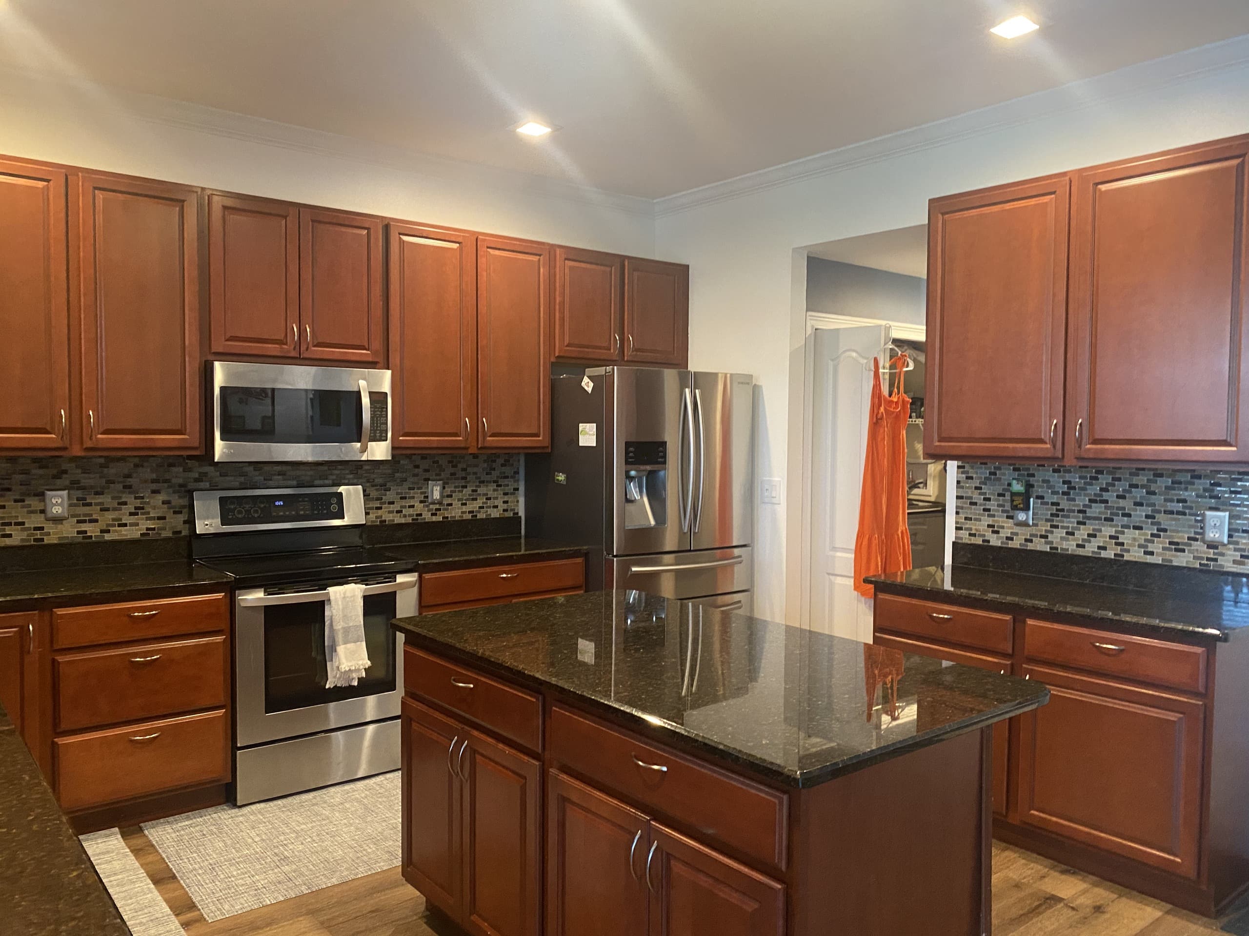 BEFORE — dated kitchen with cherry cabinets, granite counters, and mosaic backsplash (real Karhan project, Central Florida)